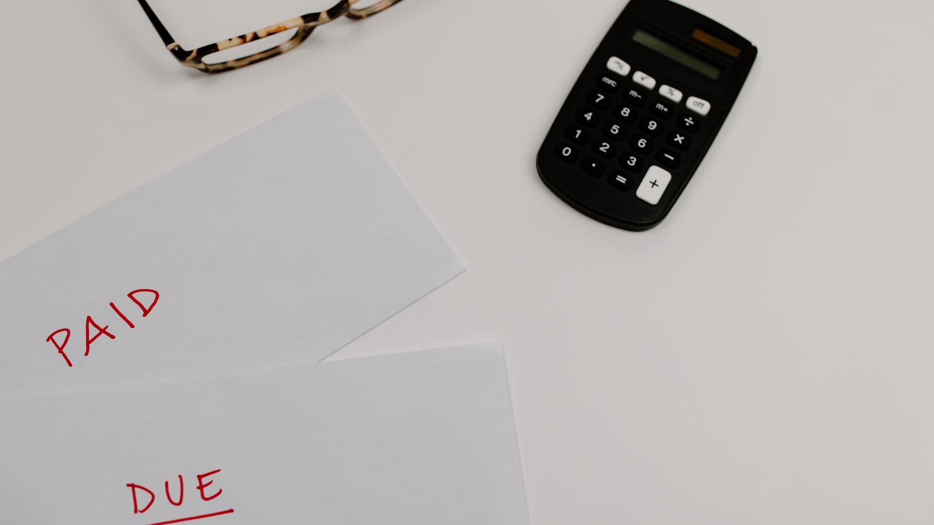 A calculator and a stack of bills on a desk