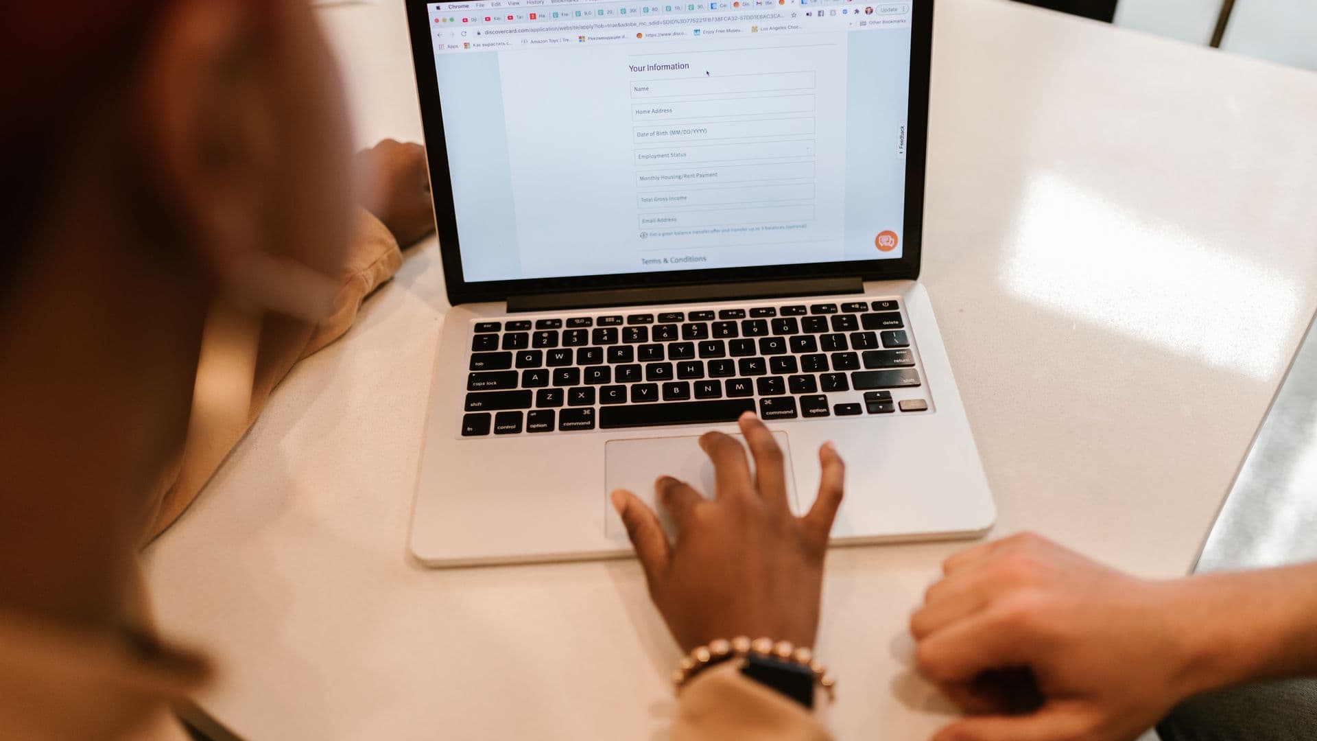 Two people filling in an online form on a laptop