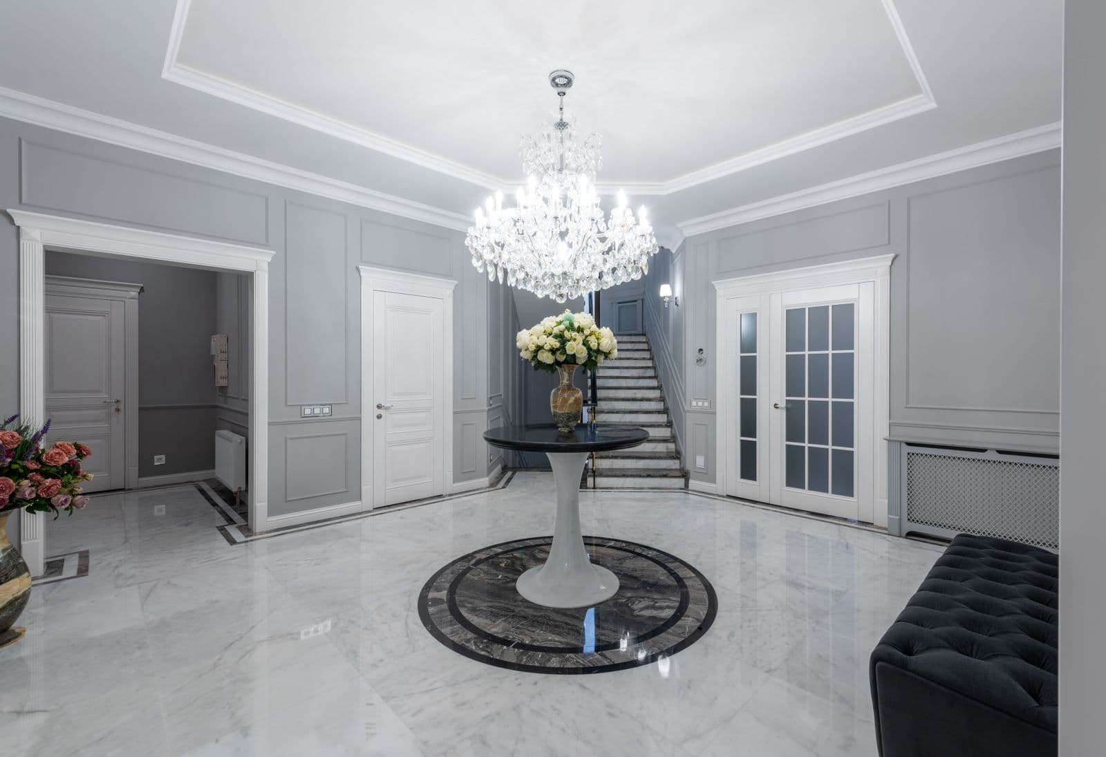 A marble entrance hall with a chandelier and a curved stair